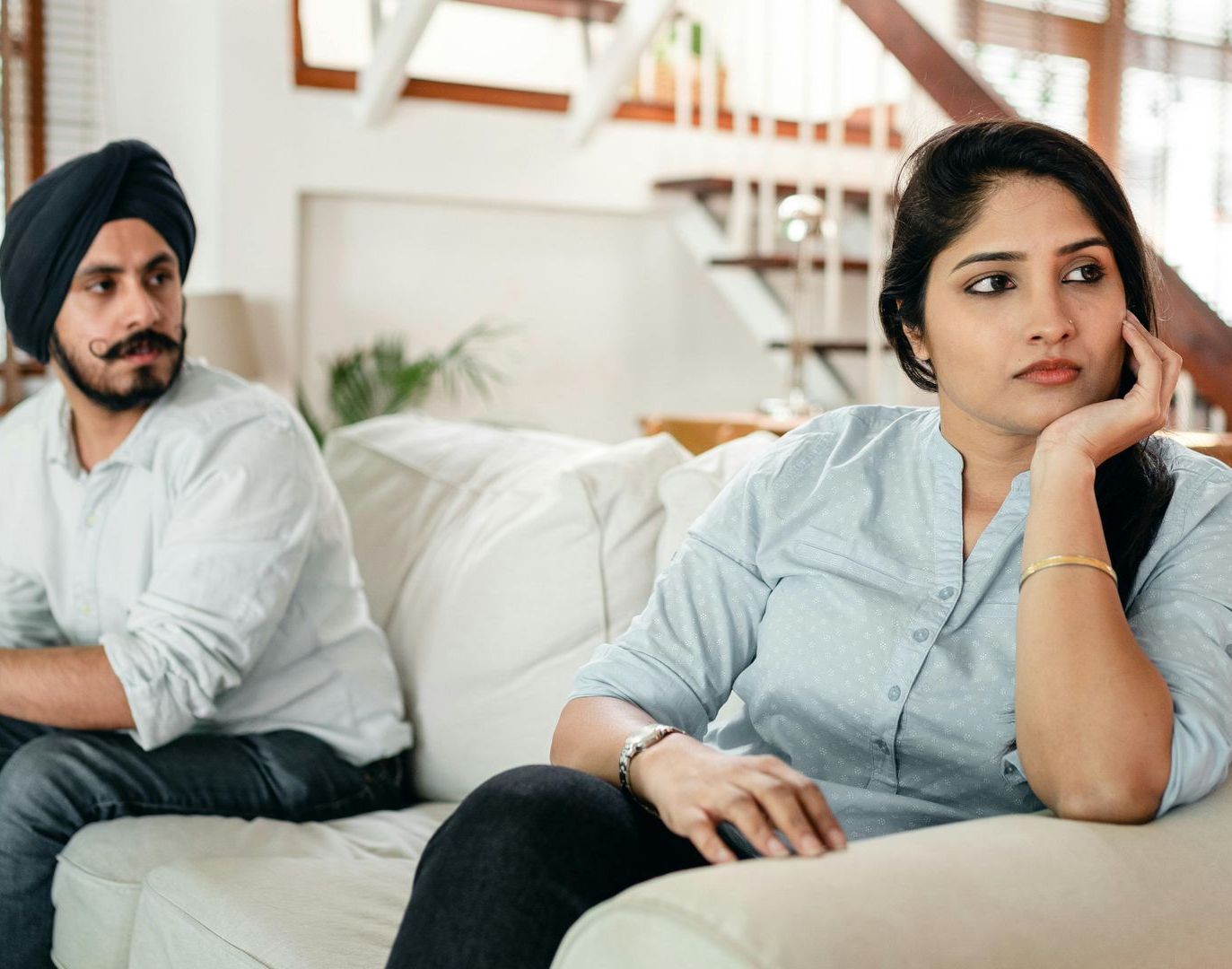 A man sits on a couch in conversation with a therapist during a session